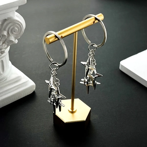 Macro view of twin star-shaped metal pendants hanging on a golden display stand