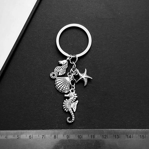 Silver marine life keychain with seahorse and starfish charms on a black surface