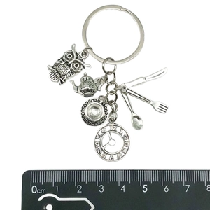 Detailed macro view of vintage Alice tea time owl and tableware alloy keychain charms