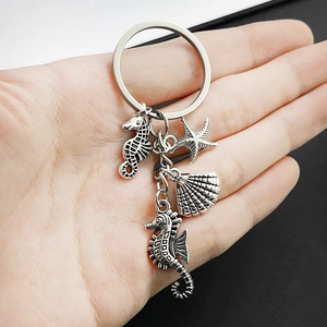 Marine metal keychain with sea horse, starfish, and scallop charms held in hand