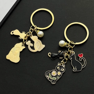 Détails des porte-clés chat en métal doré avec émail noir et accents de perles