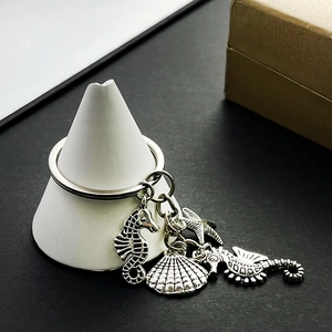 Detail of silver metal sea horse, starfish, and scallop charms on an alloy keychain hook