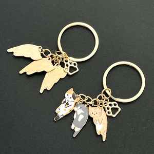 Detailed close-up of colorful enamel cat pendants and golden wing charms on keychains
