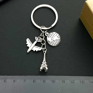 Travel keychain with airplane globe and Eiffel Tower charms on a black background