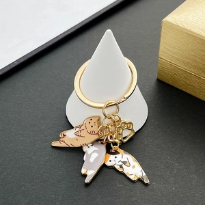 Detail of three enamel kittens and gold paw pendants on a creative metal keychain