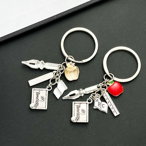 Detail of teacher-themed metal keychain with apple, ruler, and #1 Teacher blackboard charm