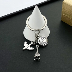 Detail of travel keychain with silver airplane, globe, and Eiffel Tower pendants