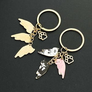 Detail of metal keychains with enamel kittens, golden angel wings, and cat paw pendants