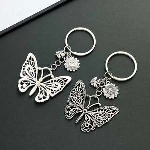 Detailed close-up of butterfly and sunflower metal keychains in silver and bronze finish