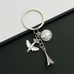 Travel themed keychain featuring airplane, globe, and Eiffel Tower in vintage silver finish