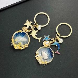 Detailed macro of golden ocean keychain with starfish, dolphin, and pearl resin charms