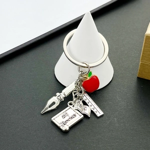 Detail view of silver #1 Teacher keychain with red apple, pen nib, ruler and ABC book charms