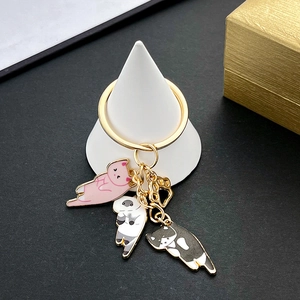 Close-up of cute cartoon enamel cat charms and golden cat paw pendant on key ring
