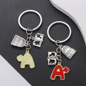 Détail de porte-clés scolaires avec pendentif A+ émaillé rouge et sac à dos en métal