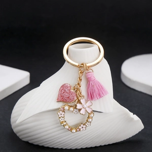 Detailed close-up of pink tassel and sequined heart charm with pearl floral accents