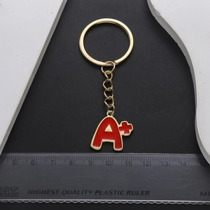 Golden keychain with red enamel A plus letter charm and metal ring for graduation gift