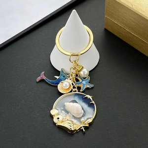 Detail of nautical keychain with blue dolphin, golden starfish, and resin shell pendant