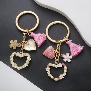 Pink tassel keychain with pearl heart charms and floral details on golden metal base