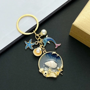 Golden ocean theme keychain with blue starfish, dolphin charm and resin shell pendant
