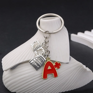 Détail des pendentifs sac à dos et livre avec breloque rouge A+ sur un porte-clés