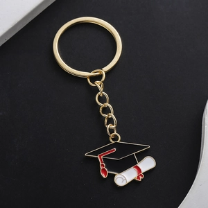 Detail of golden graduation cap keychain with black enamel and red tassel finish