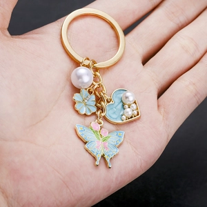 Lake blue heart pearl and flower keychain with butterfly pendant held in hand