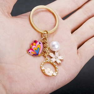 Portachiavi dorato con farfalla in smalto rosa, fiore di ciliegio, perla e anello di cristalli