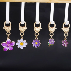Set of 5 purple enamel floral keychains with gold heart lobster clasps on dark background