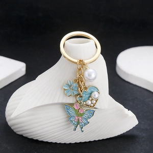 Detail of blue heart pearl and enamel butterfly keychain on white scallop display stand