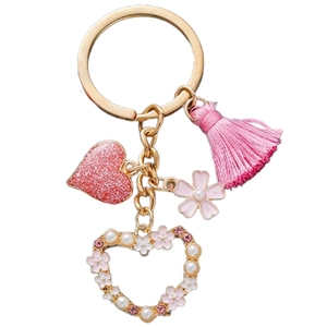Close-up of pink tassel, glitter heart pendant, and pearl flower charms on a golden keychain