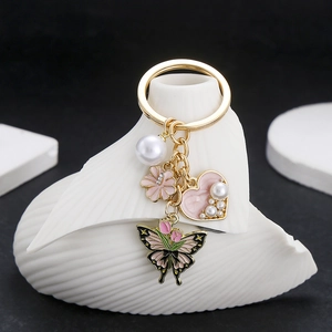 Detailansicht der rosa Emaille-Blumen und Schmetterlingsanhänger mit Perlen auf Goldkette