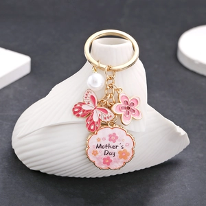 Détail d'un papillon rose et d'un pendentif Mother's Day sur un porte-clés doré chic
