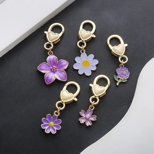 Detailed macro of purple enamel flower pendants with heart-shaped golden lobster clasps