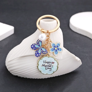 Dettaglio portachiavi dorato con farfalla blu, perla e ciondolo Happy Mother's Day