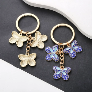 Golden butterfly keychains with blue enamel and textured metal pendants for accessories