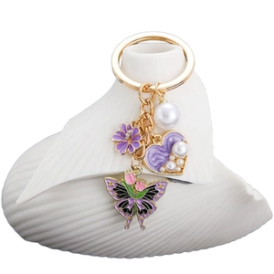 Purple heart and pearl tulip butterfly keychain with gold hardware on white decor
