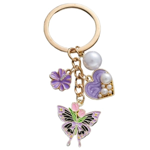 Detail of golden keychain with purple enamel flower, pearl heart, and tulip butterfly pendant