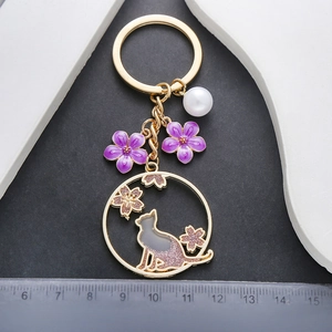 Porte-clés chat doré avec couronne de fleurs de cerisier mauves et breloque perle blanche
