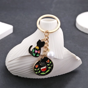 Détail du porte-clés doré avec pendentifs chat en émail noir et perle élégante