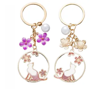 Détails porte-clé chat fleurs de cerisier violettes avec perles blanches et doré