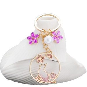 Porte-clés couronne chat doré avec fleurs de cerisier émaillées mauves et perle blanche