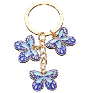 Detailed view of golden butterfly keychain with blue enamel oil drip craft on white background