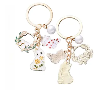 Detail view of cat pendant keychain with white oil-drop charms and gold-tone metal finish