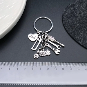 Détail du porte-clés fête des pères argenté avec pendentifs cœur, moto et outils sur règle