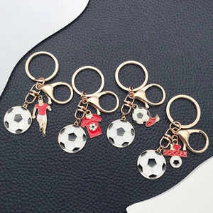 Detailed macro view of four golden soccer keychains with enamel football and shoe charms