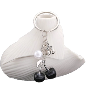 Portachiavi con ciliegia nera con perla bianca e anello in metallo su vaso bianco