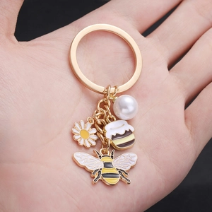 Porte-clés avec marguerite, abeille et perle comprenant de charmants pendentifs dorés