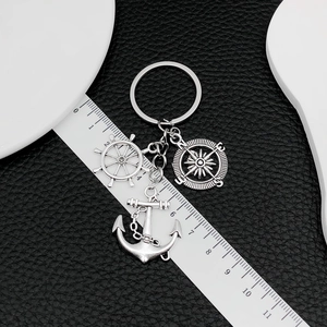 Nautical keychain with anchor, rudder and compass charms measured against a ruler