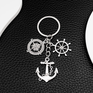 Nautical keychain detail with silver anchor, compass, and ship wheel on black leather