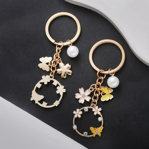 Golden butterfly and flower pearl keychains for handbags on a two-tone background